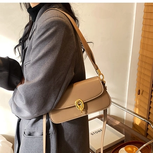 Detail einer beigen Leder-Schultertasche mit goldener Ringschnalle am Verschluss