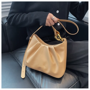 Detail of pleated dumpling bag in beige with a chunky gold chain strap decoration