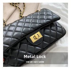 Close-up of black quilted leather bag with elegant golden hardware lock and chain strap