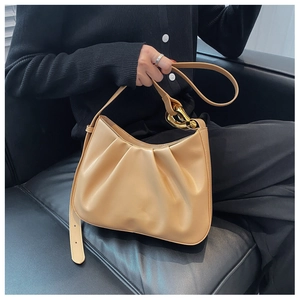 Detail of beige pleated cloud bag with large gold buckle and adjustable strap