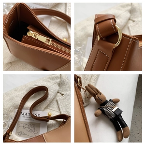 Gros plan des surpiqûres sur le sac besace en cuir marron avec fermeture éclair dorée et lapin