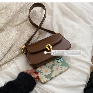 Größenvergleich der braunen Vintage-Baguette-Tasche neben einem Smartphone auf Decke
