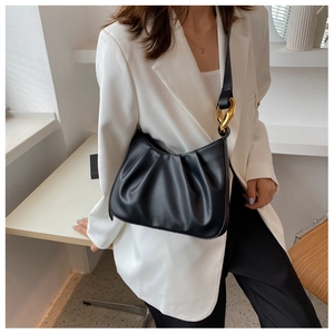 Detail of black pleated shoulder bag with stylish gold chain strap and matte leather finish