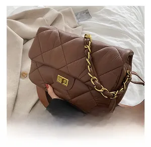 Détail du sac bandoulière matelassé marron foncé avec chaîne dorée et fermoir pivotant