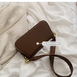 Rückseite der dunkelbraunen Leder-Umhängetasche mit breitem Gurt und goldener Hardware