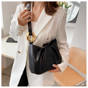 Detail of black pleated cloud bucket bag with large gold hardware ring and smooth PU texture