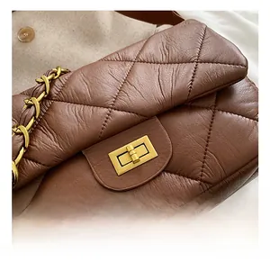 Détail d'un sac bandoulière en cuir marron matelassé avec fermoir rotatif doré