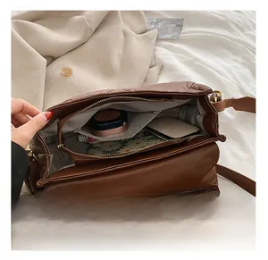 Vue détaillée de l'intérieur du sac matelassé marron avec rouge à lèvres et maquillage