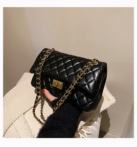 Detail of black quilted shoulder bag with gold chain strap and metallic twist lock