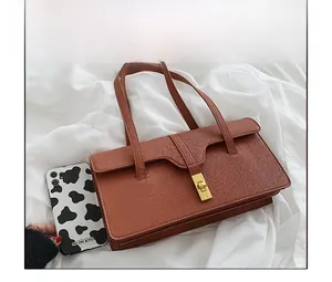 Close-up of brown leather bag with lychee texture and gold clasp showing size comparison