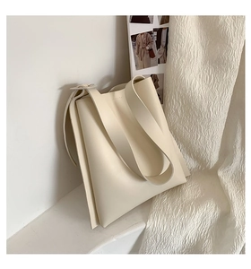 Detail view of large cream tote bag with accordion side pleats and wide shoulder strap