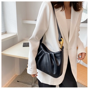 Detail of black pleated cloud bucket bag with chunky gold chain hardware on model