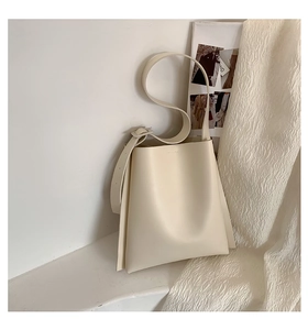 Detail of minimalist cream-white leather tote bag with smooth texture and adjustable strap