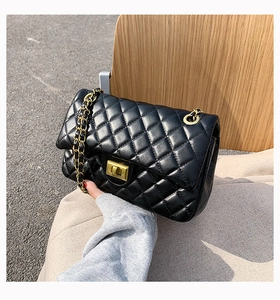 Detail of black quilted leather shoulder bag with gold metal chain and rotary lock