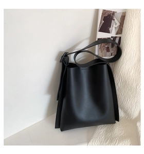Detail of minimalist black matte bucket bag featuring adjustable wide shoulder strap