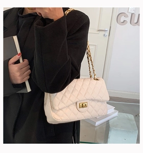 Close-up of beige quilted leather crossbody bag with gold chain strap and turn-lock