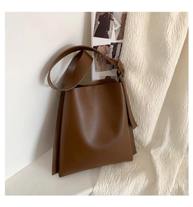 Detailed view of dark brown leather tote bag texture with wide shoulder strap design