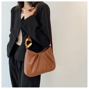 Brown ruched cloud bucket bag with gold chain link on a model wearing black blazer