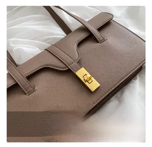 Detailed macro view of the golden rectangular twist lock and lychee grain brown leather
