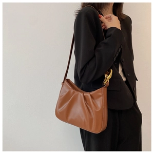 Detail of caramel pleated hobo bag showing soft faux leather and golden chain strap