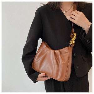 Detail of a brown ruched cloud bucket bag with chunky gold hardware and vegan leather