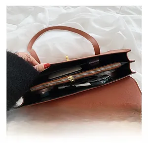 Interior detail of a brown leather shoulder bag with spacious compartments and golden lock