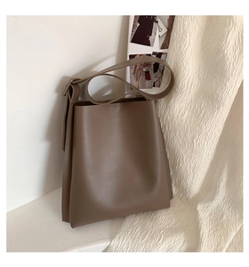 Detail of adjustable strap and matte leather finish on a brown shoulder bucket bag