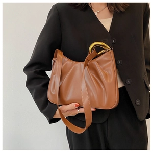 Detail of caramel brown ruched cloud bag featuring stylish gold metal handles and smooth PU texture