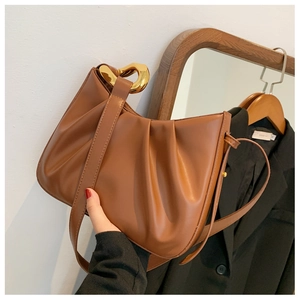 Close-up of brown pleated cloud bag with a gold U-shaped buckle and long strap