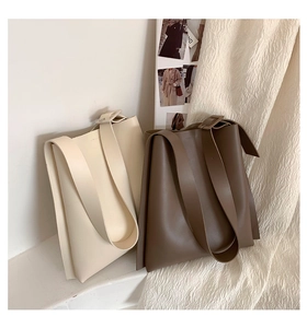 Detail of minimalist leather tote bags in cream and brown with adjustable shoulder straps