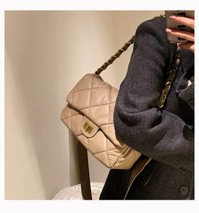 Détail du sac à bandoulière matelassé beige avec chaîne dorée et fermoir pivotant carré