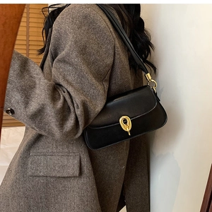 Detail der schwarzen Leder-Achseltasche mit goldener Schnalle und passendem Schultergurt