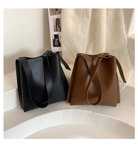 Detailed view of adjustable wide straps on minimalist black and dark brown leather tote bags