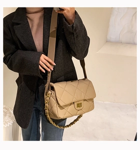 Sac bandoulière beige matelassé avec chaîne dorée porté par un mannequin