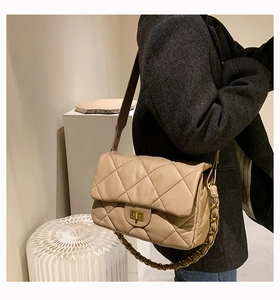 Mannequin portant un sac bandoulière beige matelassé avec chaîne dorée et fermoir