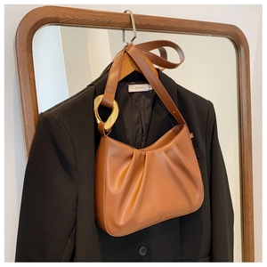 Close-up of brown pleated dumpling bag with elegant gold metal buckle detail