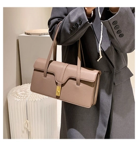Detail of taupe square shoulder bag with gold metal buckle on female model in grey blazer
