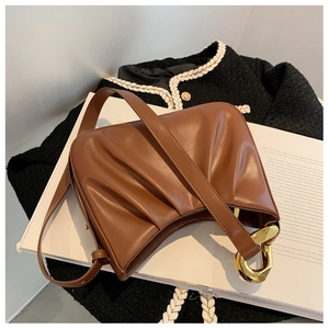 Macro detail of brown pleated leather cloud bag with elegant gold ring hardware buckle