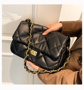 Détail du sac bandoulière en cuir noir matelassé avec chaîne dorée et fermoir rotatif
