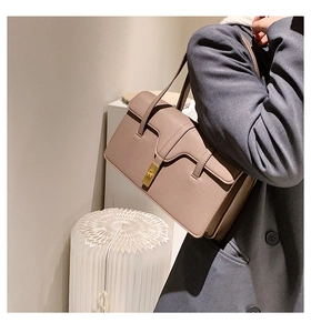 Detail view of a taupe rectangular underarm bag with elegant gold turn-lock metal clasp