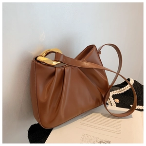 Close-up of caramel brown ruched leather bag with chunky gold chain and slim strap