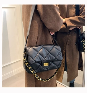 Gros plan sur le sac bandoulière en cuir noir matelassé avec chaîne dorée et fermoir