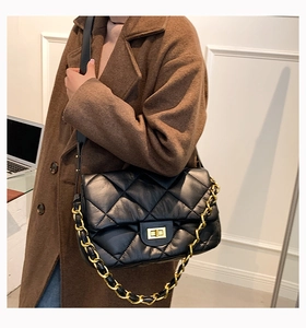 Détail d'un sac bandoulière noir matelassé avec chaîne dorée et fermoir pivotant élégant