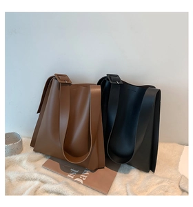 Detail of minimalist leather tote bags in brown and black with wide shoulder straps
