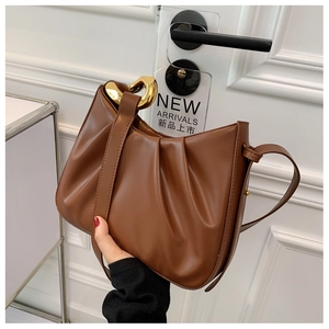 Detail of brown pleated leather cloud bag with chunky gold metal chain handle