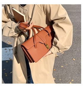 Detail of caramel leather shoulder bag showing the golden square twist lock and accordion side