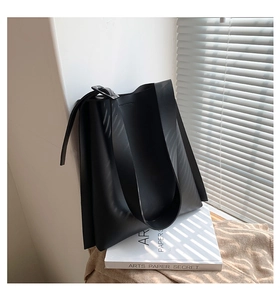 Detail of black matte PU leather tote bag with grainy texture and wide shoulder strap