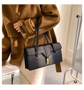 Detail of vintage black leather shoulder bag featuring a gold rectangular twist lock