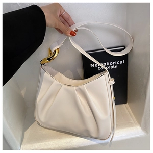 Detail view of cream ruched bucket bag featuring a decorative gold knot metal buckle accent