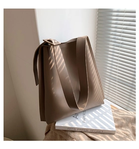 Artistic shadow play on a minimalist brown faux leather tote bag with wide strap